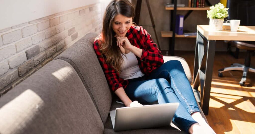 femme qui fait du télétravail chez elle sur son canapé gris 