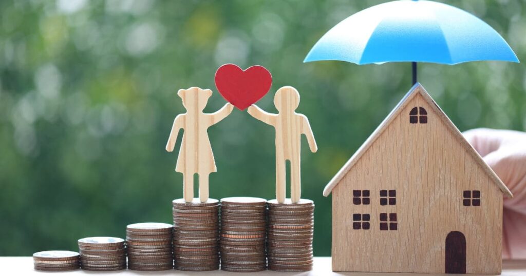  couple d'amoureux tenant un cœur debout sur une pile de pièces de monnaie avec une maison modèle sous le parapluie sur un fond vert naturel